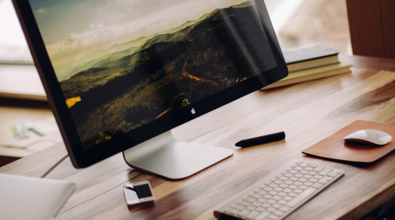 space gray iMac near Magic Keyboard on brown wooden computer desk during daytime