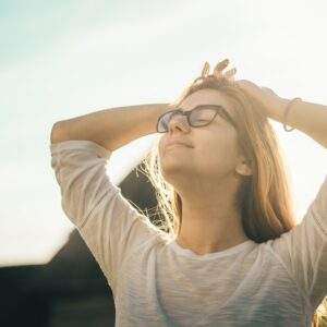 woman in white crew-neck T-shirt holding her head