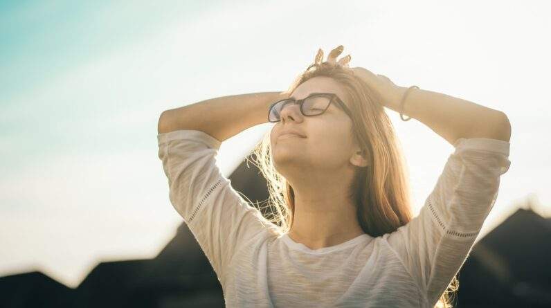 woman in white crew-neck T-shirt holding her head