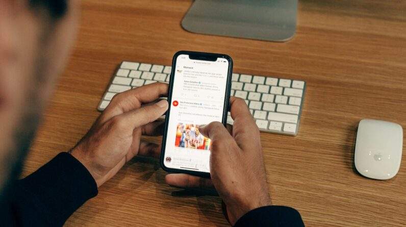 man holding phone while leaning on table