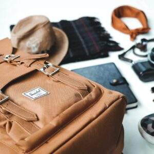 closeup photo of brown leather bag near sunglasses and shoes