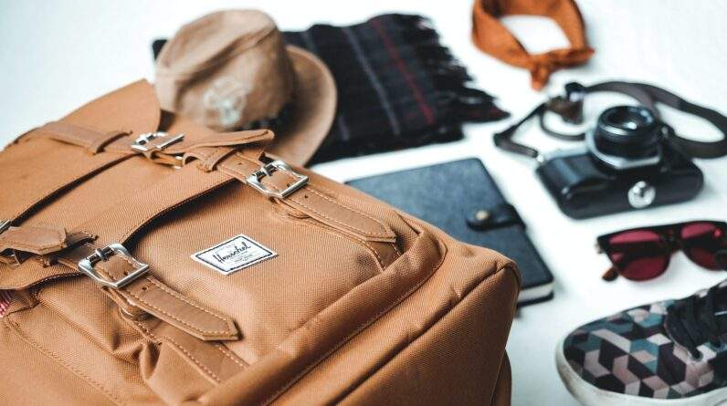 closeup photo of brown leather bag near sunglasses and shoes